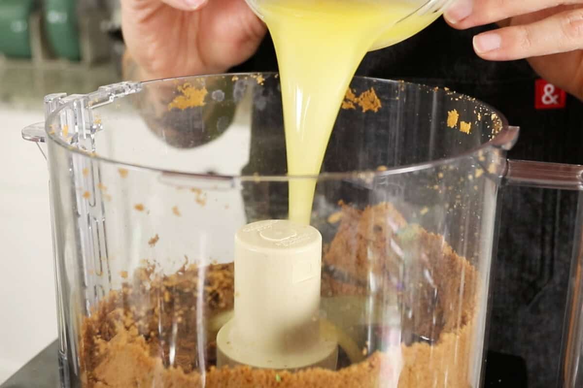 adding butter to cookie crust in a food processor