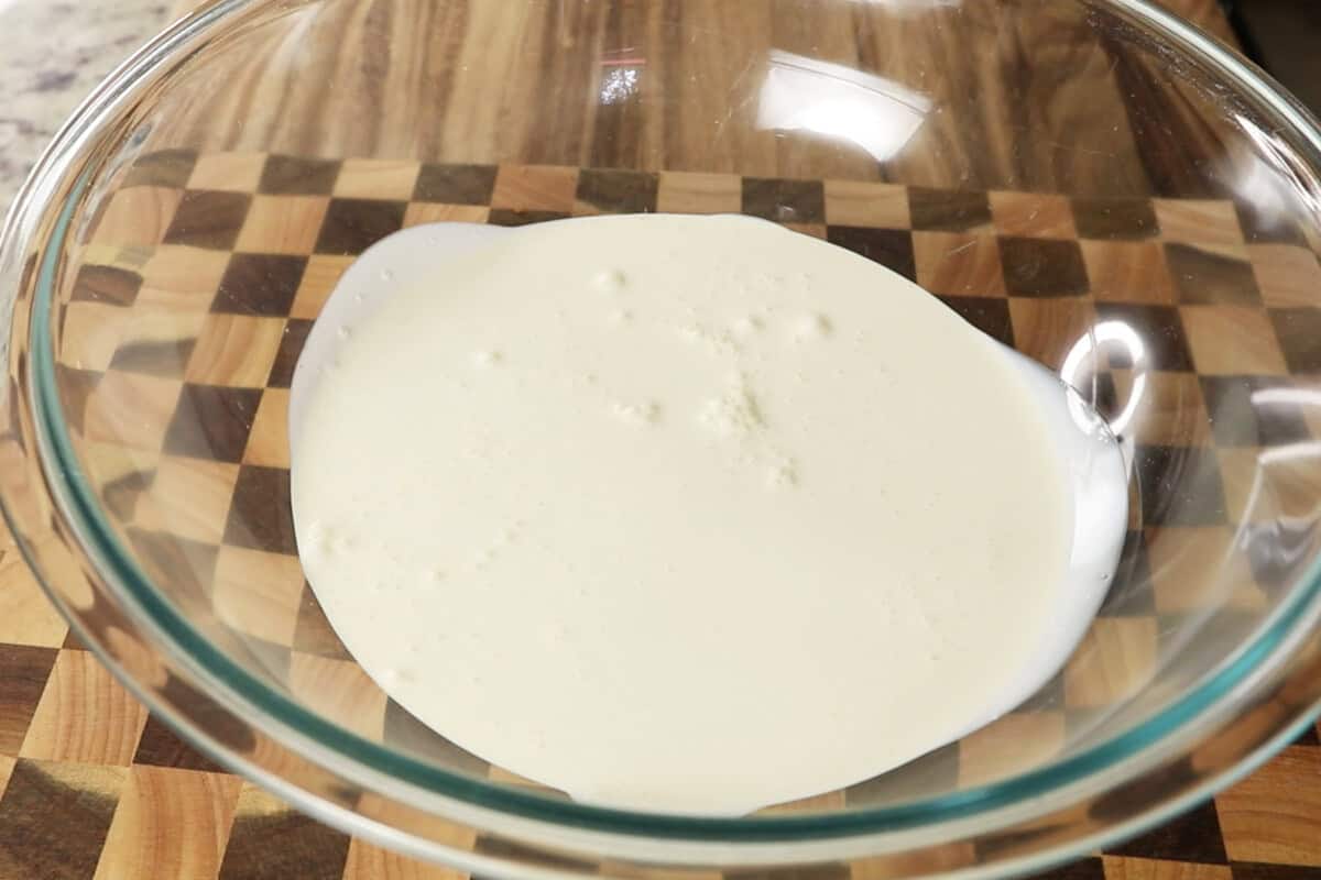 adding heavy cream to a large glass bowl