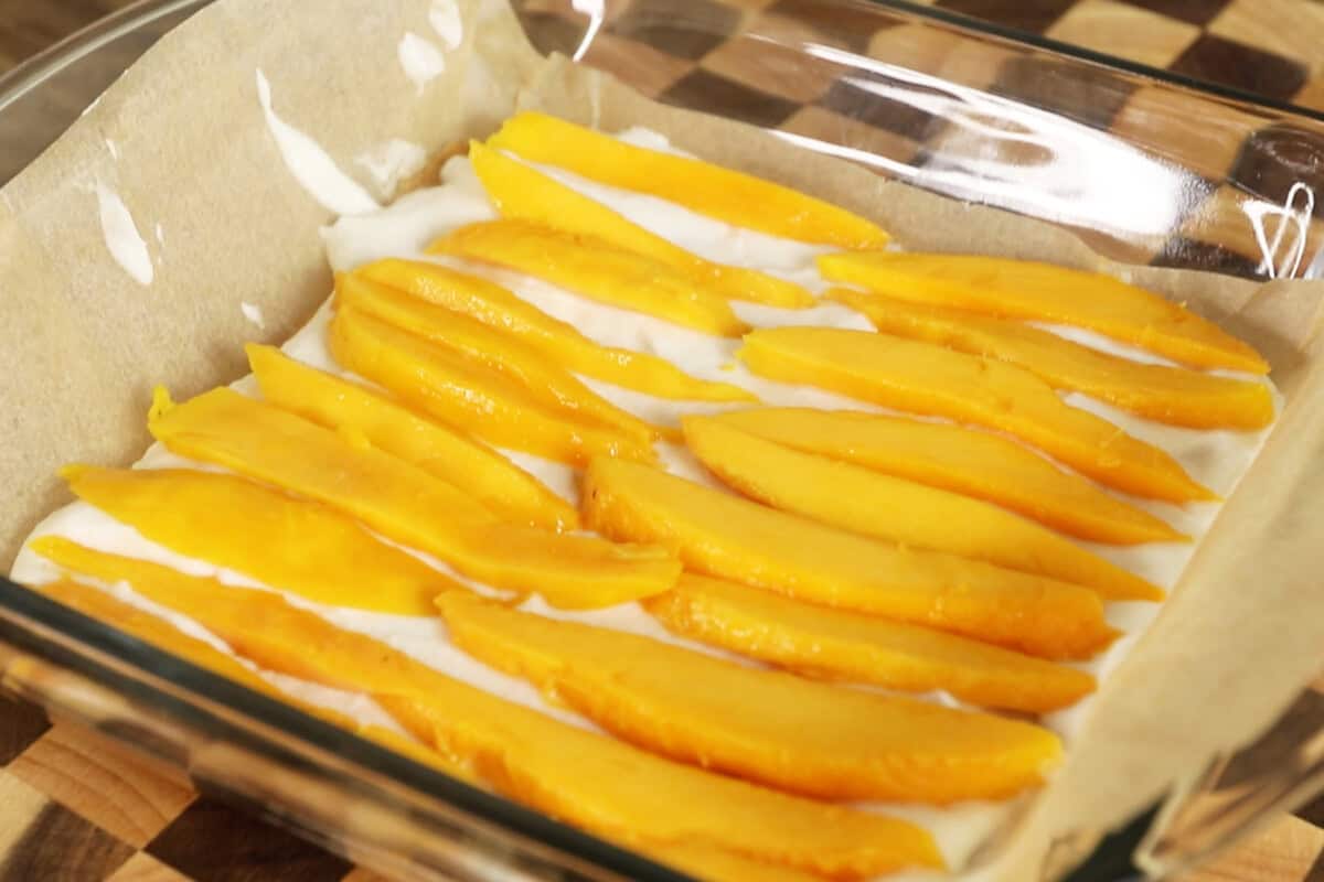 adding a layer of cream and slices of mango