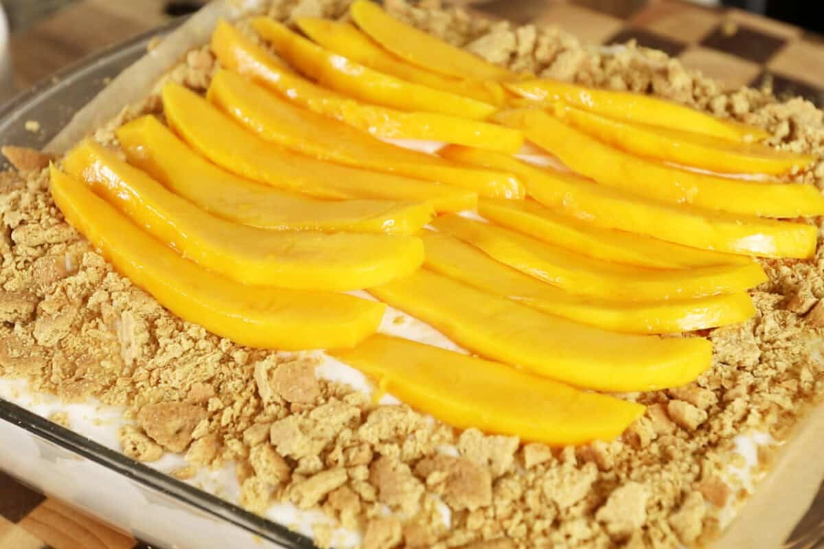 adding slices of mango on top of mango float