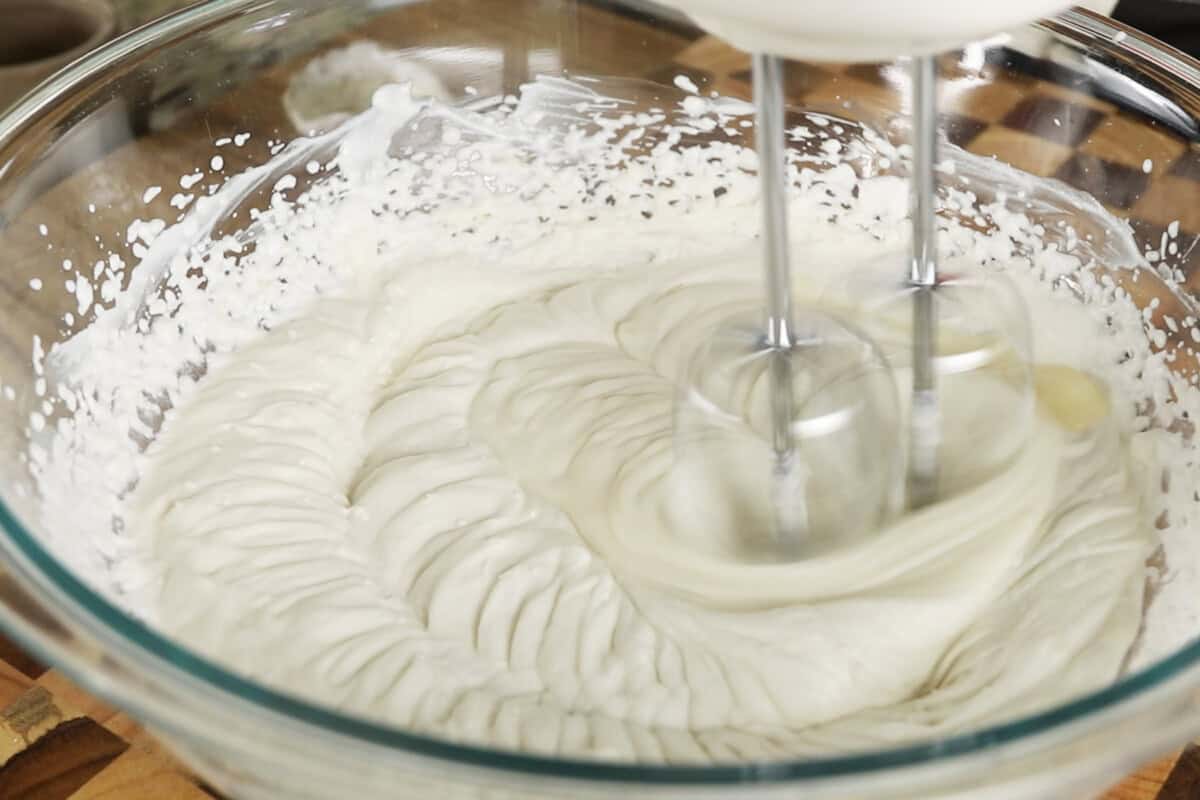 using a hand mixer to whip heavy cream in large bowl