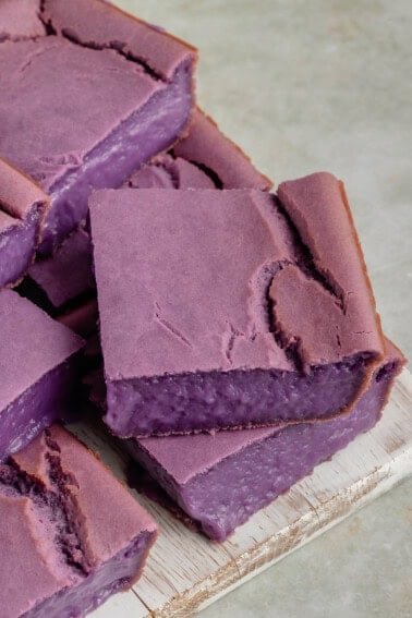 stack of homemade vegan ube butter mochi on white wood board