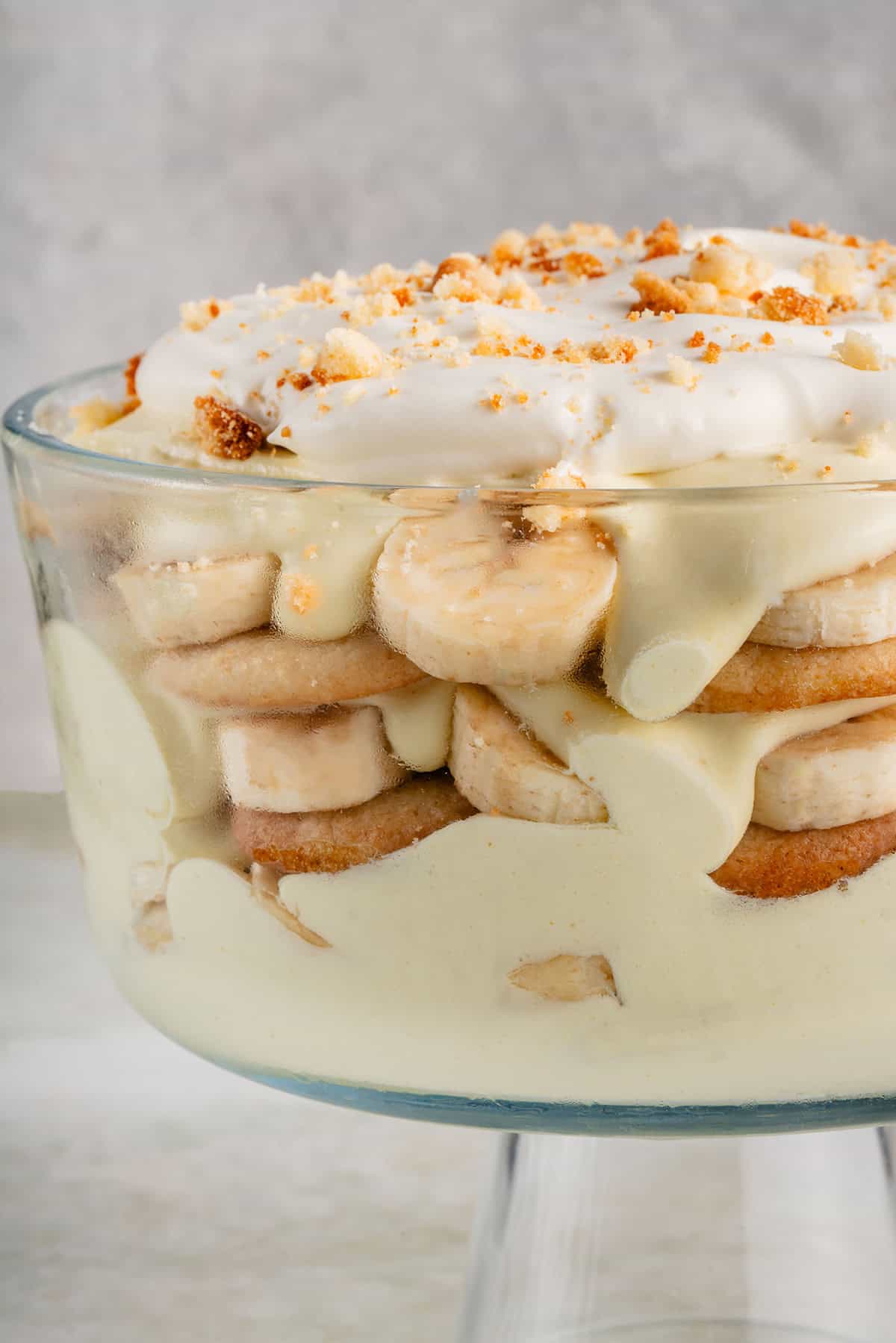 close up of vegan banana pudding with whipped cream in clear trifle dish