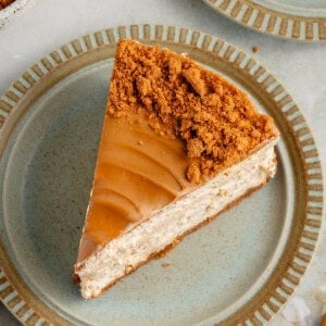 overhead image of vegan biscoff cheesecake on a blue plate with cookies and crumbs surrounding it