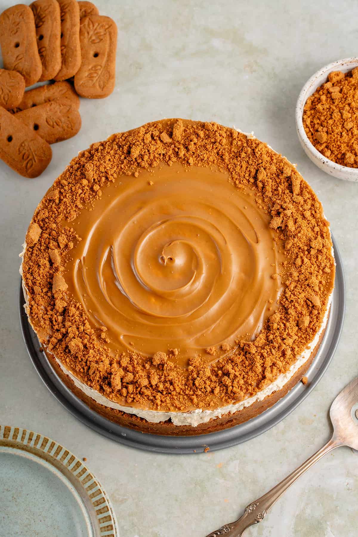 overhead of vegan biscoff cheesecake surrounded by cookies and cookie crumbs and a spatula