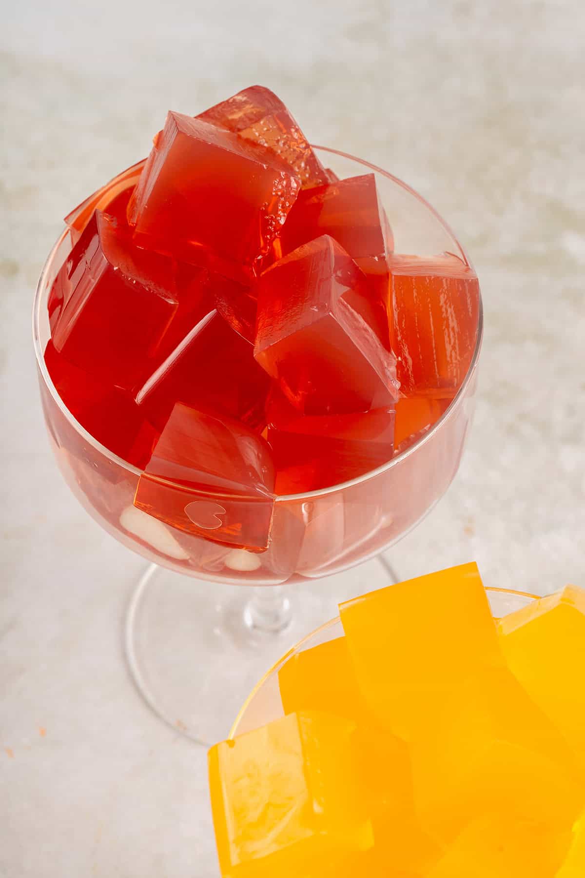 tall glass filled with red and yellow cubes of vegan jello