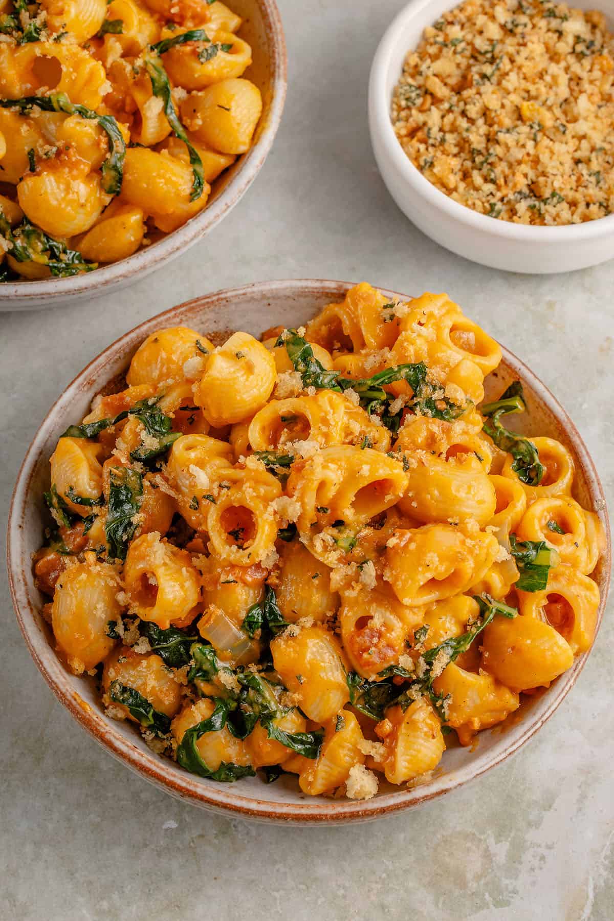 photo of creamy vegan pumpkin mac and cheese in a bowl with toasted breadcrumbs