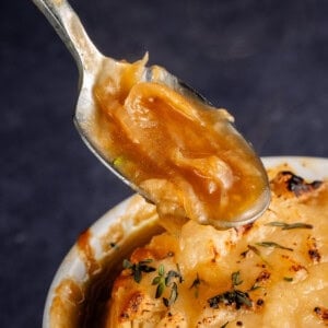 spoon full of french onion soup over bowl