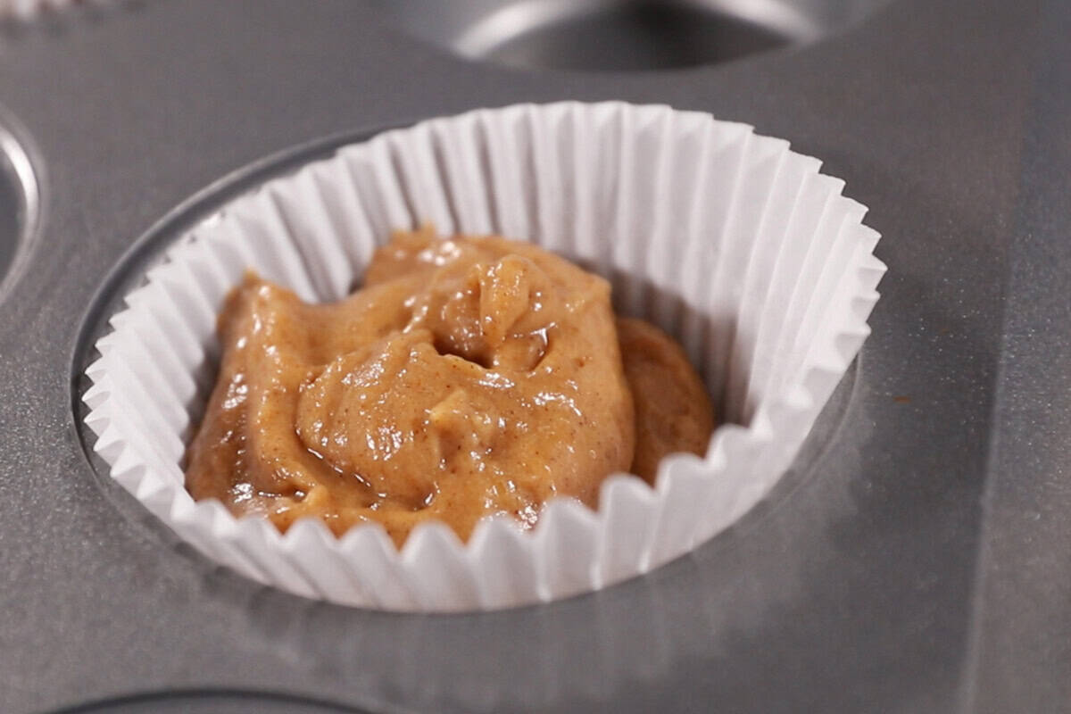 filling muffin pan with batter for pumpkin cream cheese muffins