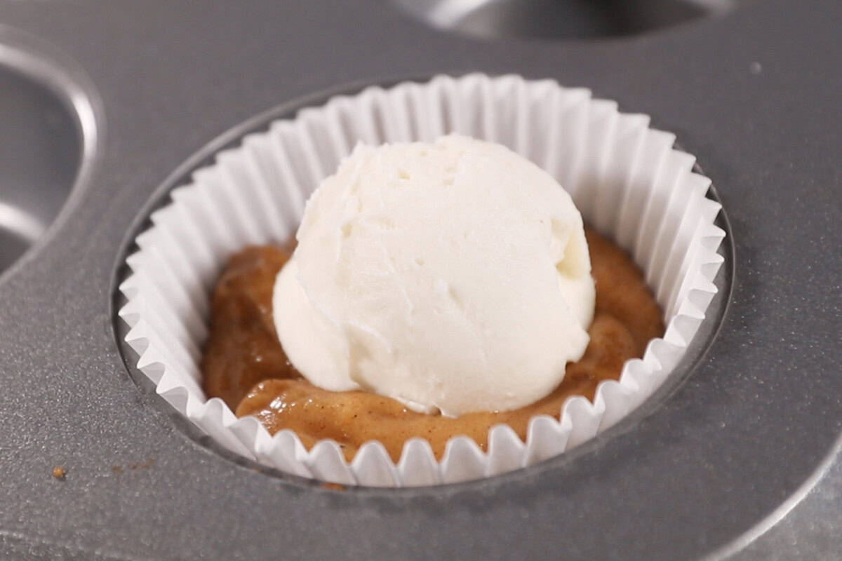 filling muffin pan with batter and cream cheese for pumpkin cream cheese muffins