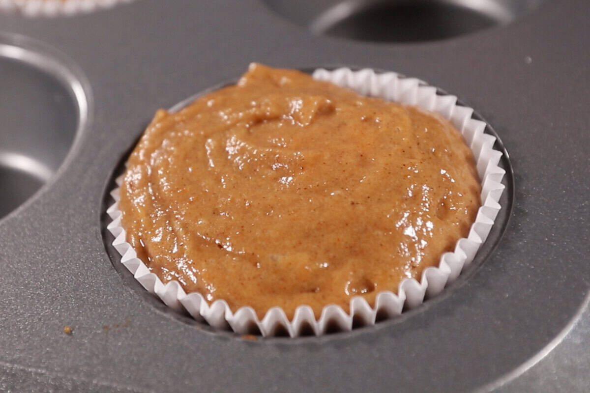 filling muffin pan with batter and cream cheese for pumpkin cream cheese muffins