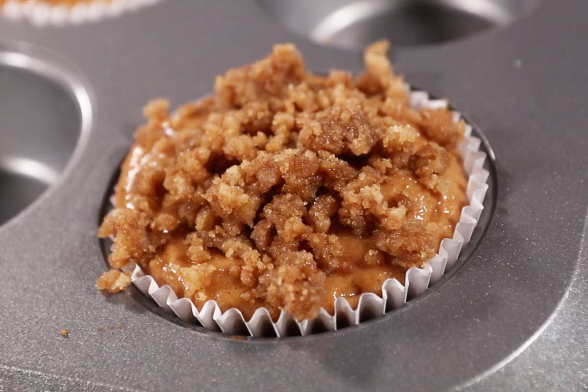 muffin pan with unbaked batter and streusel for pumpkin cream cheese muffins