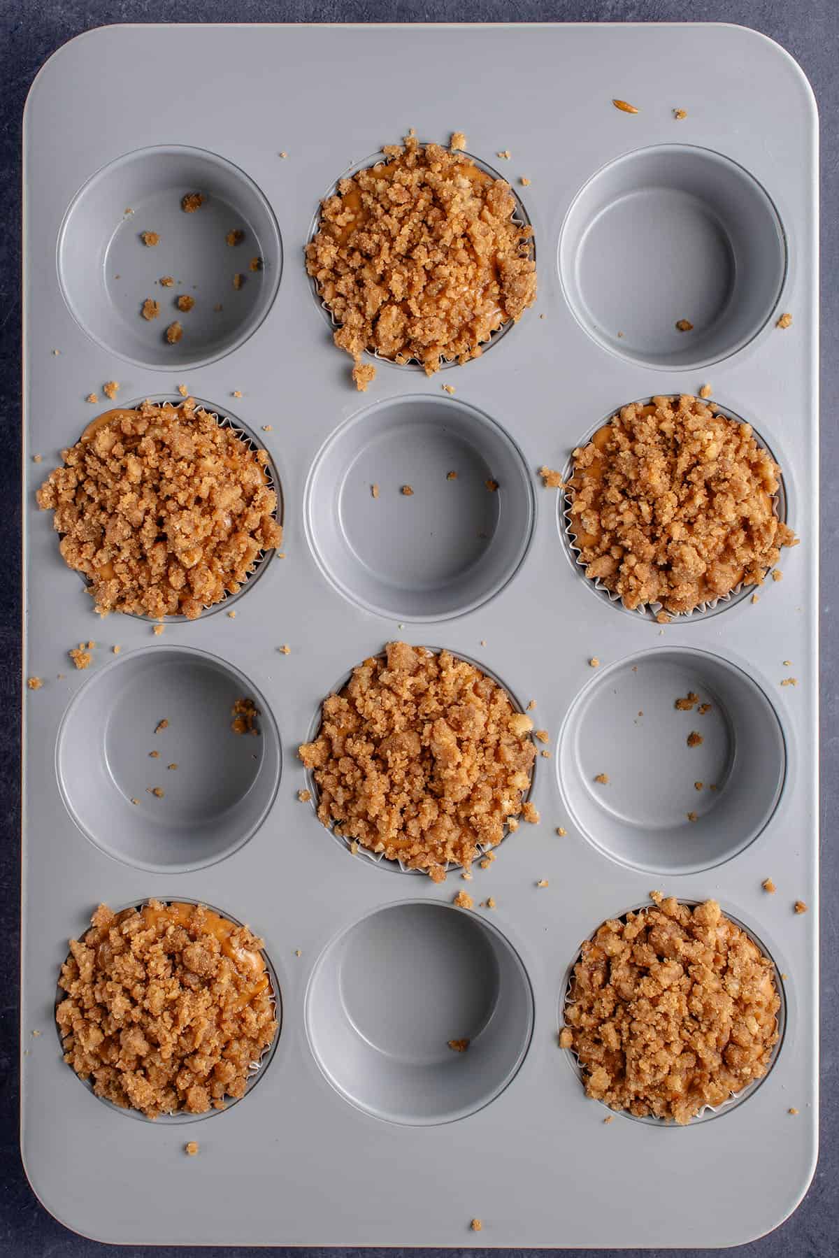 overhead photo of unbaked pumpkin cream cheese muffins in pan with brown parchment liners