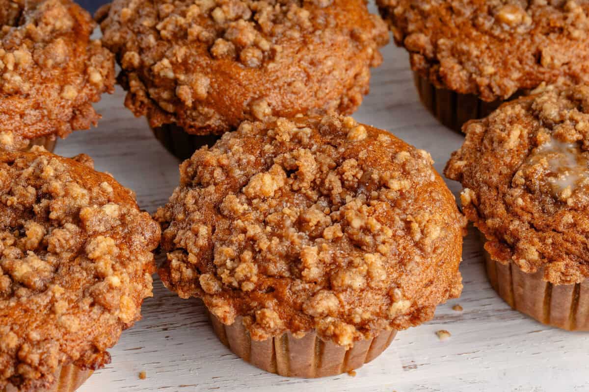 overhead horizontal photo of freshly baked pumpkin cream cheese muffins on white board