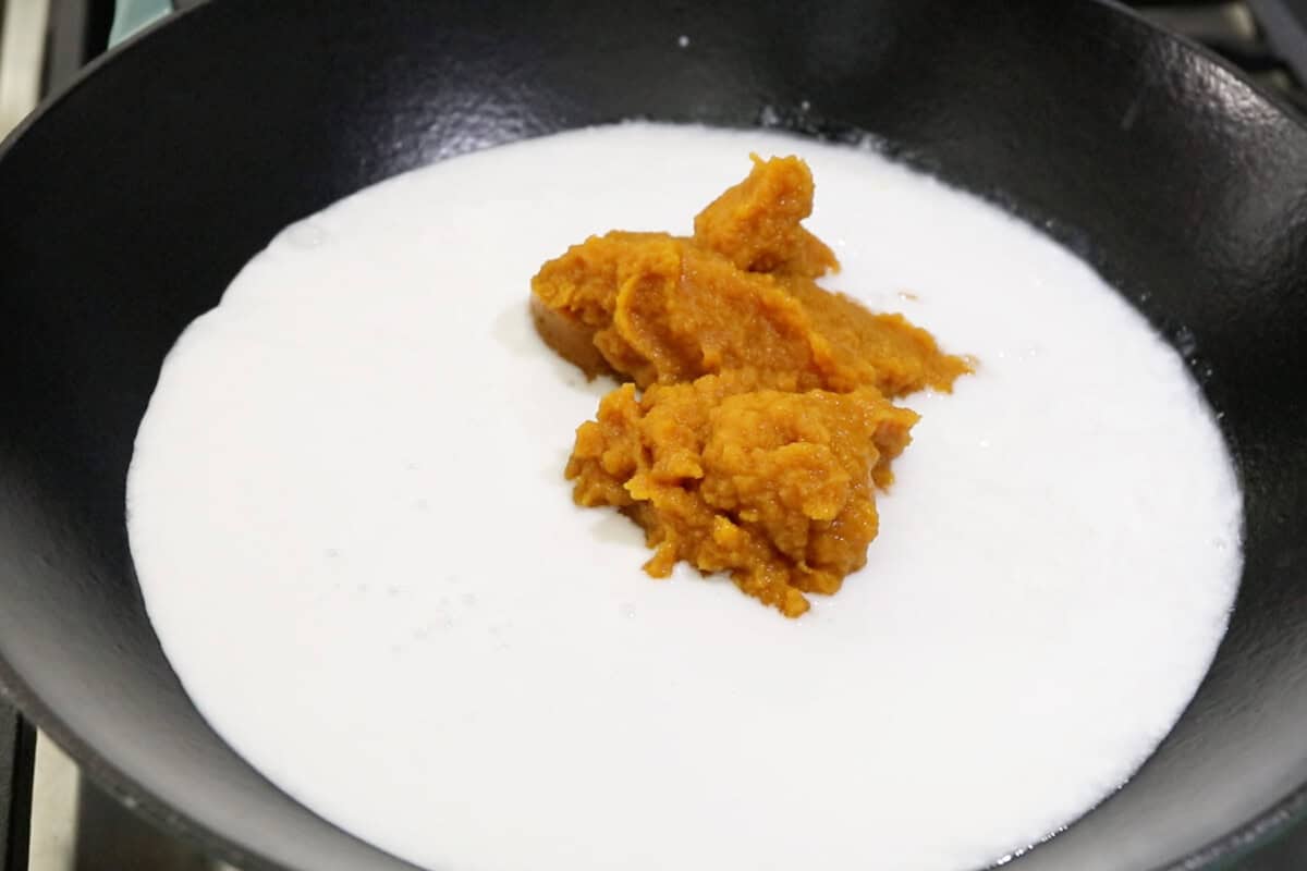 preparing a pumpkin coconut mixture in a wok for Filipino pumpkin biko