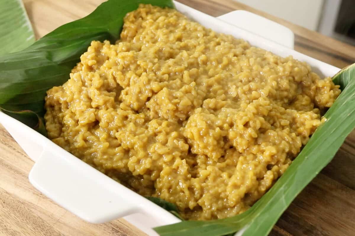 pouring warm Biko Kalabasa (Pumpkin Biko) into pan lined with banana leaves