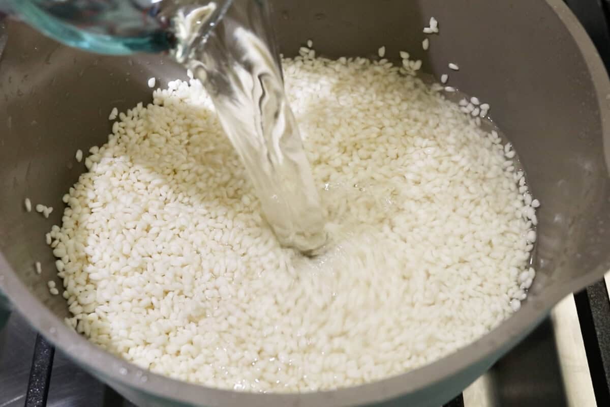 pouring water into a pot with uncooked sweet rice