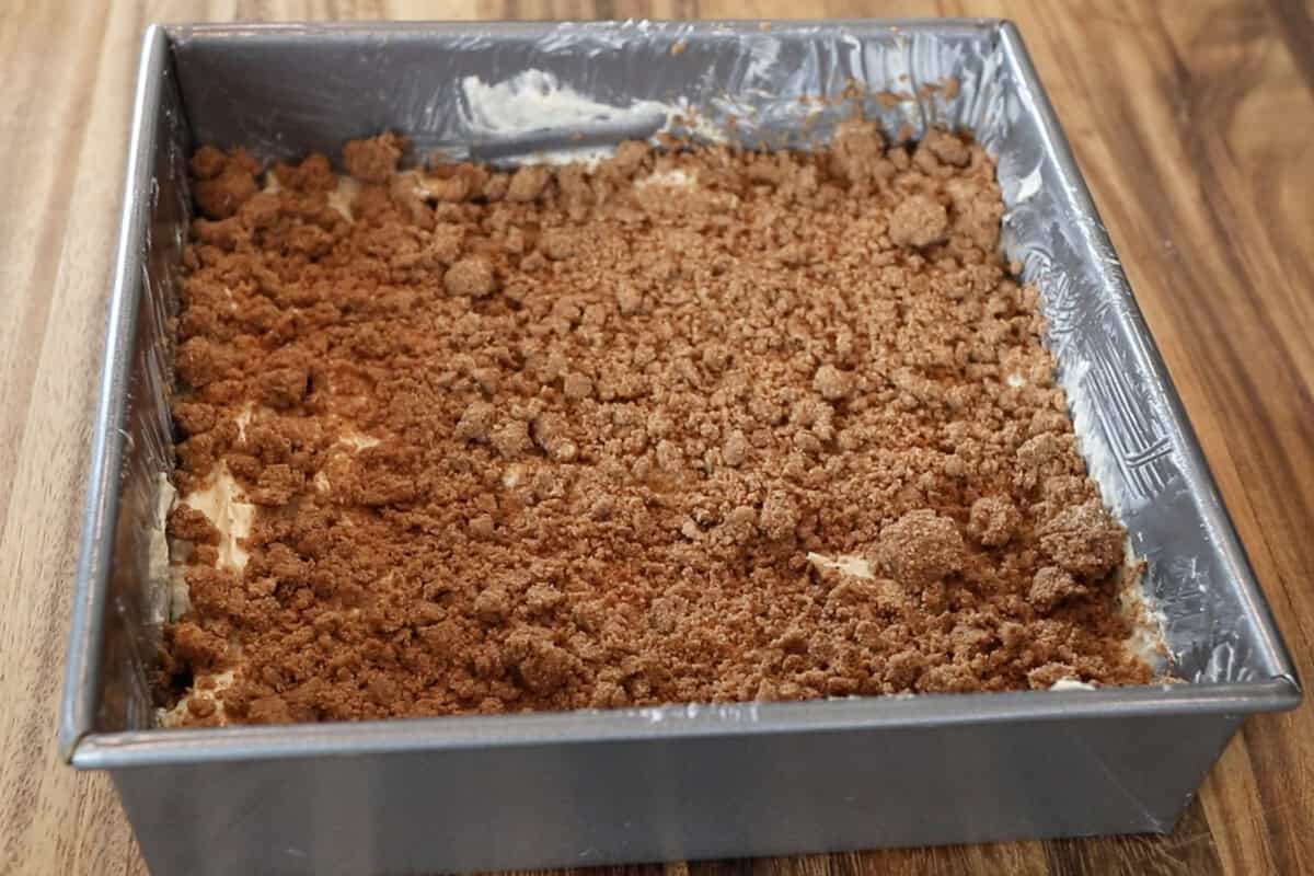 streusel topping layered over cake batter for vegan coffee cake in baking dish