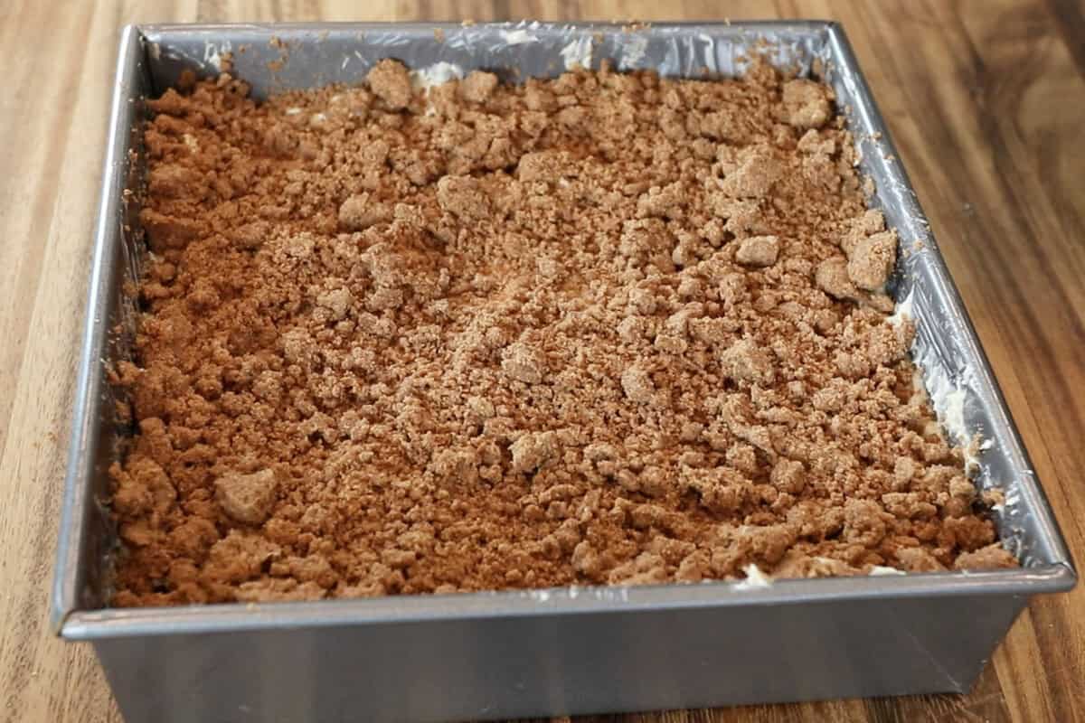 streusel topping layered over cake batter for vegan coffee cake in baking dish before baking