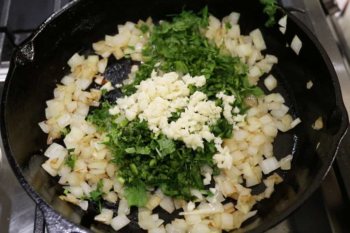 adding cilantro and garlic to the skillet