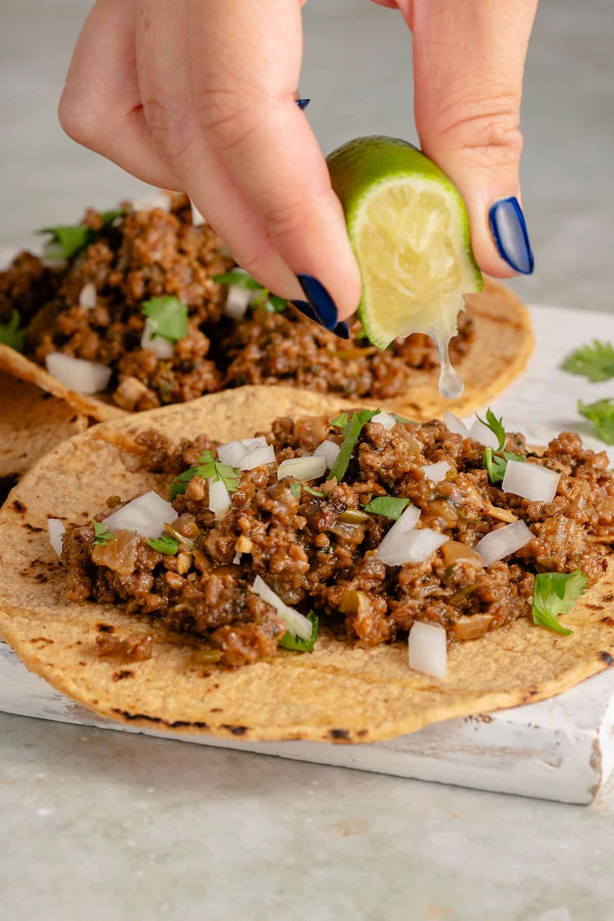 squeezing a lime onto vegan ground beef tacos