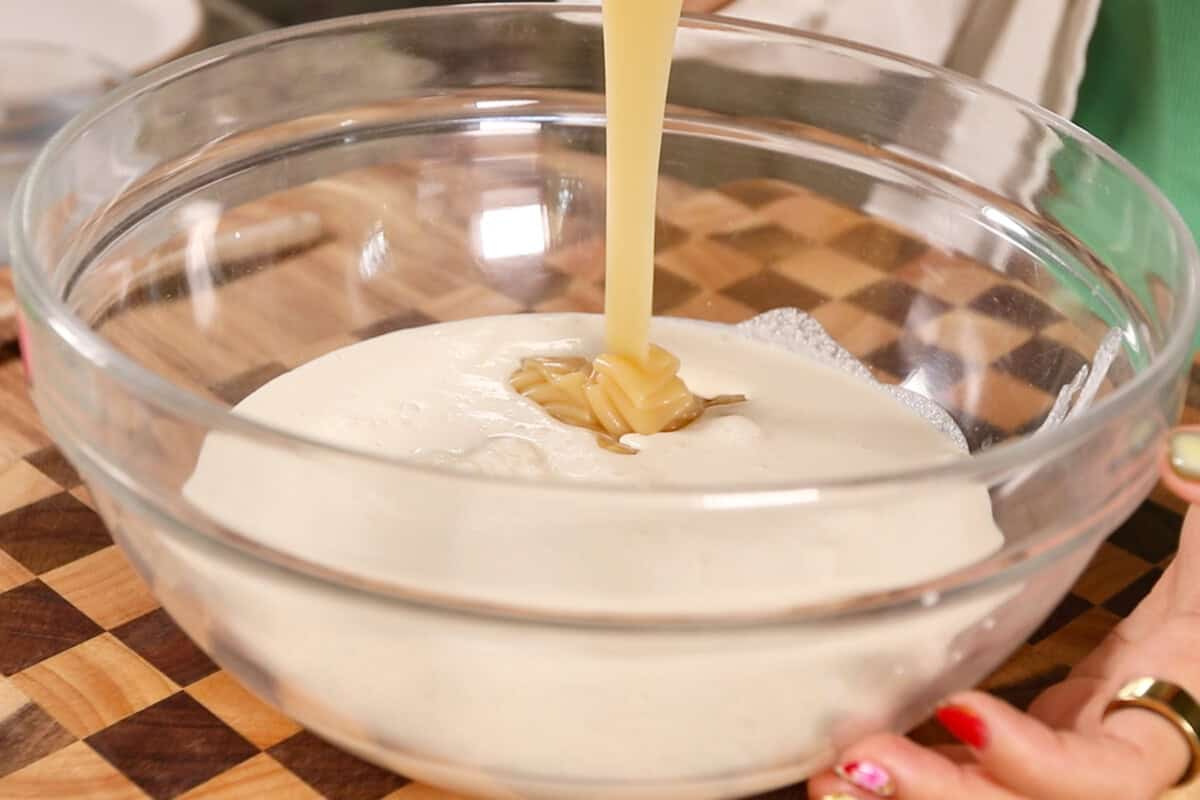 making Filipino Buko Pandan Salad in large glass bowl