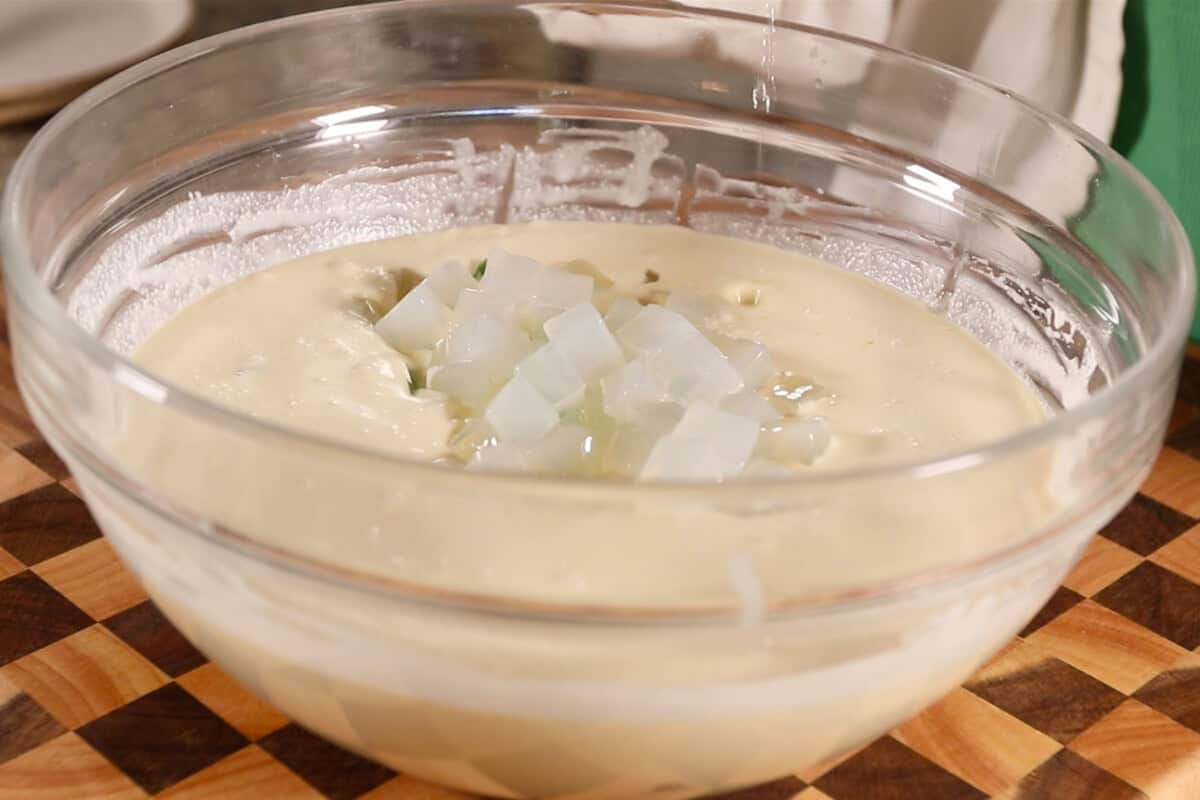 making Filipino Buko Pandan Salad in large glass bowl