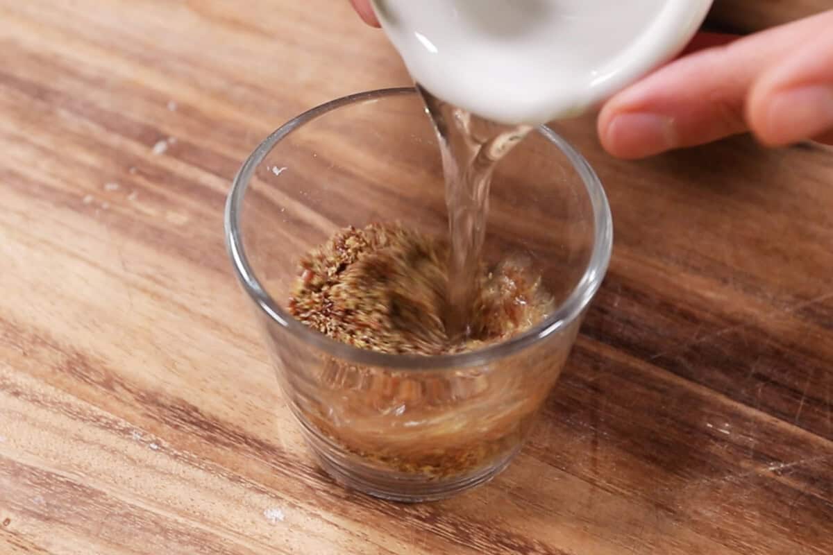 adding water to a small cup of flaxseed meal