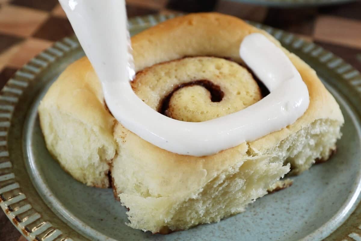 piping the Creme Brûlée topping onto the cinnamon roll