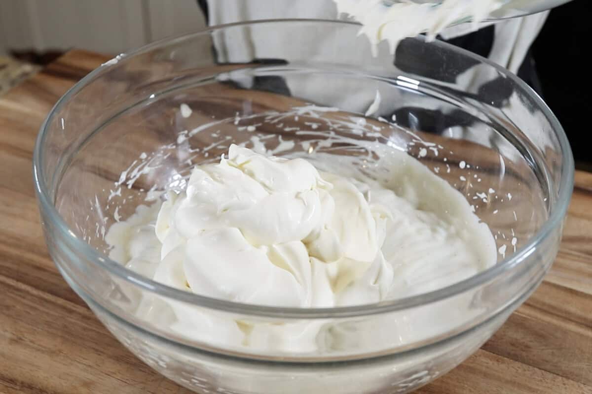 adding whipped heavy cream to the bowl of custard