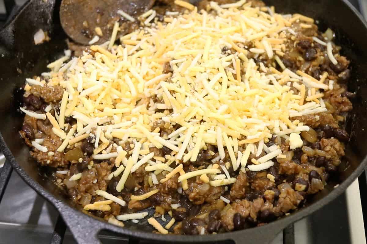 adding vegan cheese to the filling in the skillet