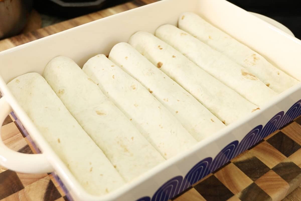 adding filled tortillas to the baking dish