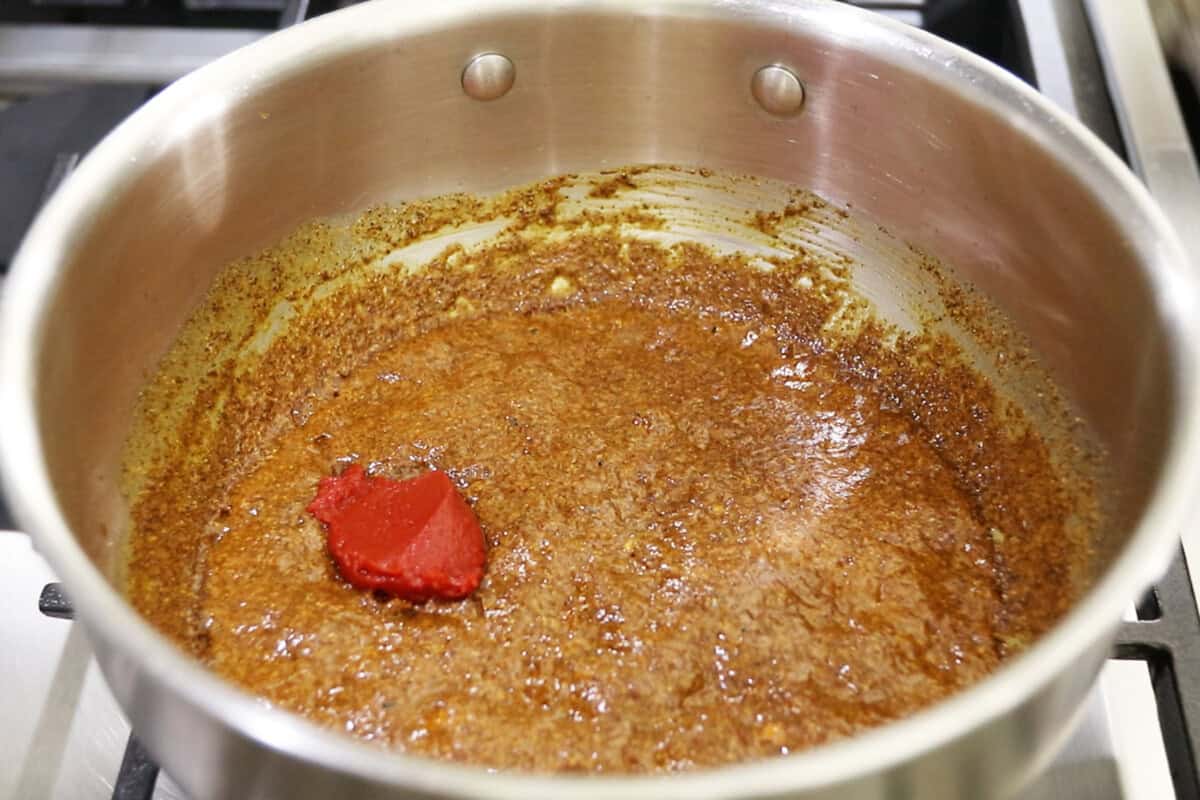 adding tomato paste to the pot