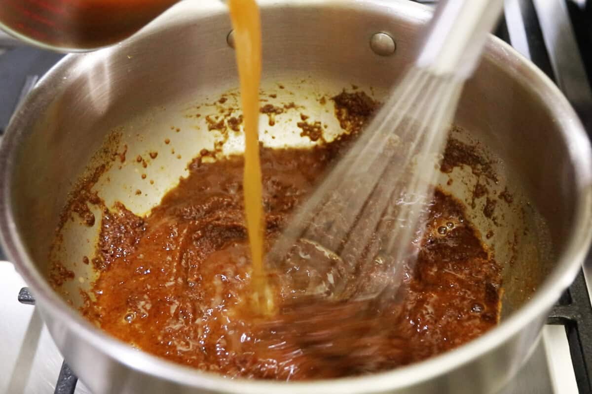 whisking in the broth to the enchilada sauce