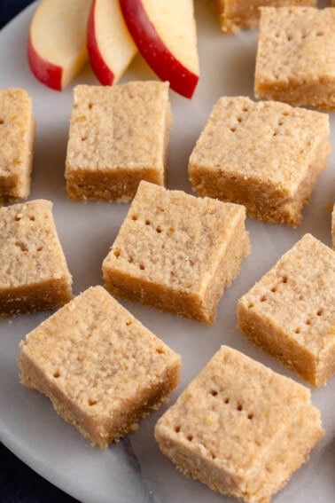 cinnamon apple shortbread bars on a white platter with sliced apples