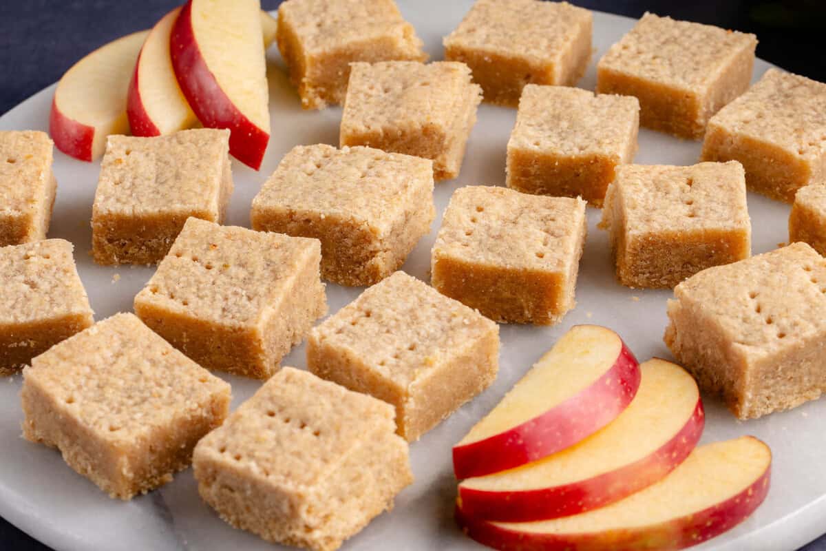 cinnamon apple shortbread bars on a white platter with sliced apples