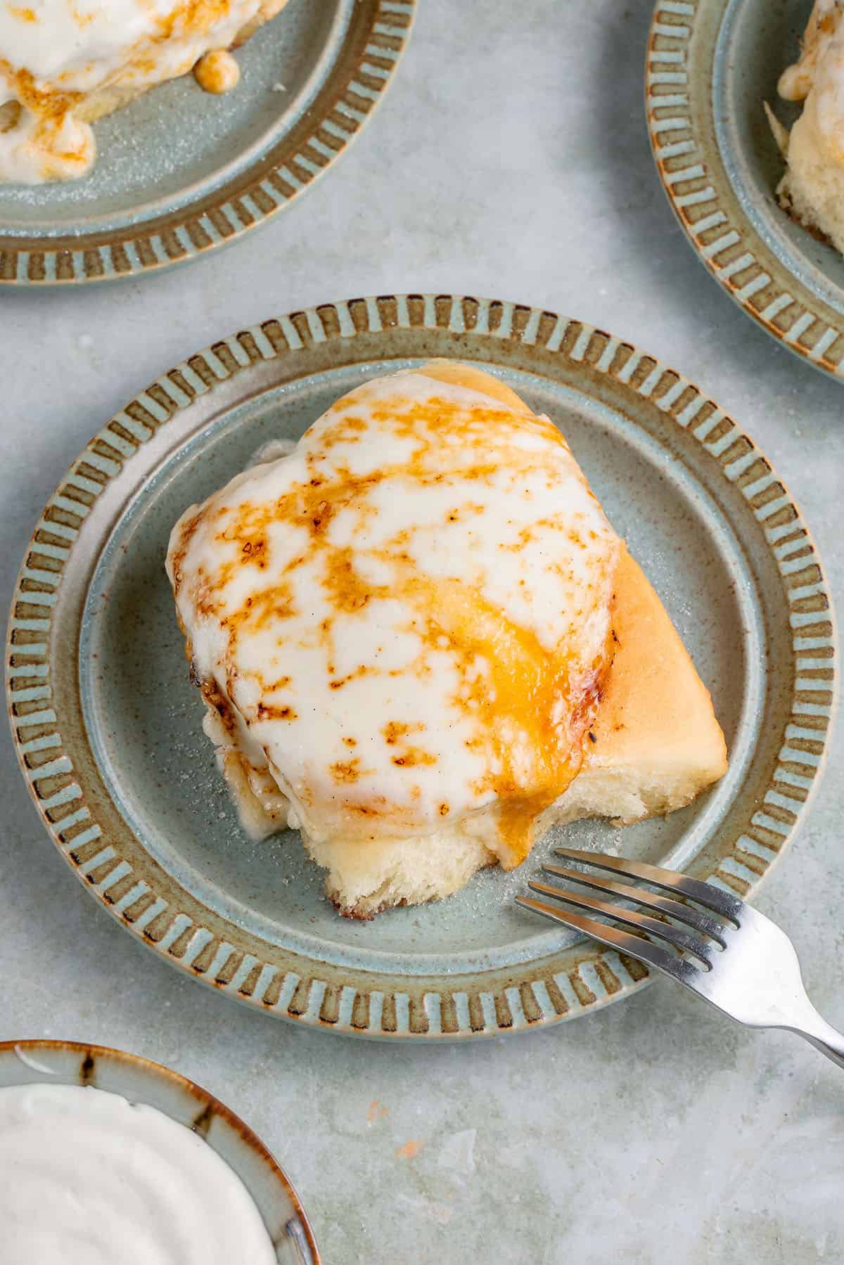 overhead of Creme Brûlée cinnamon roll on blue plate with a fork