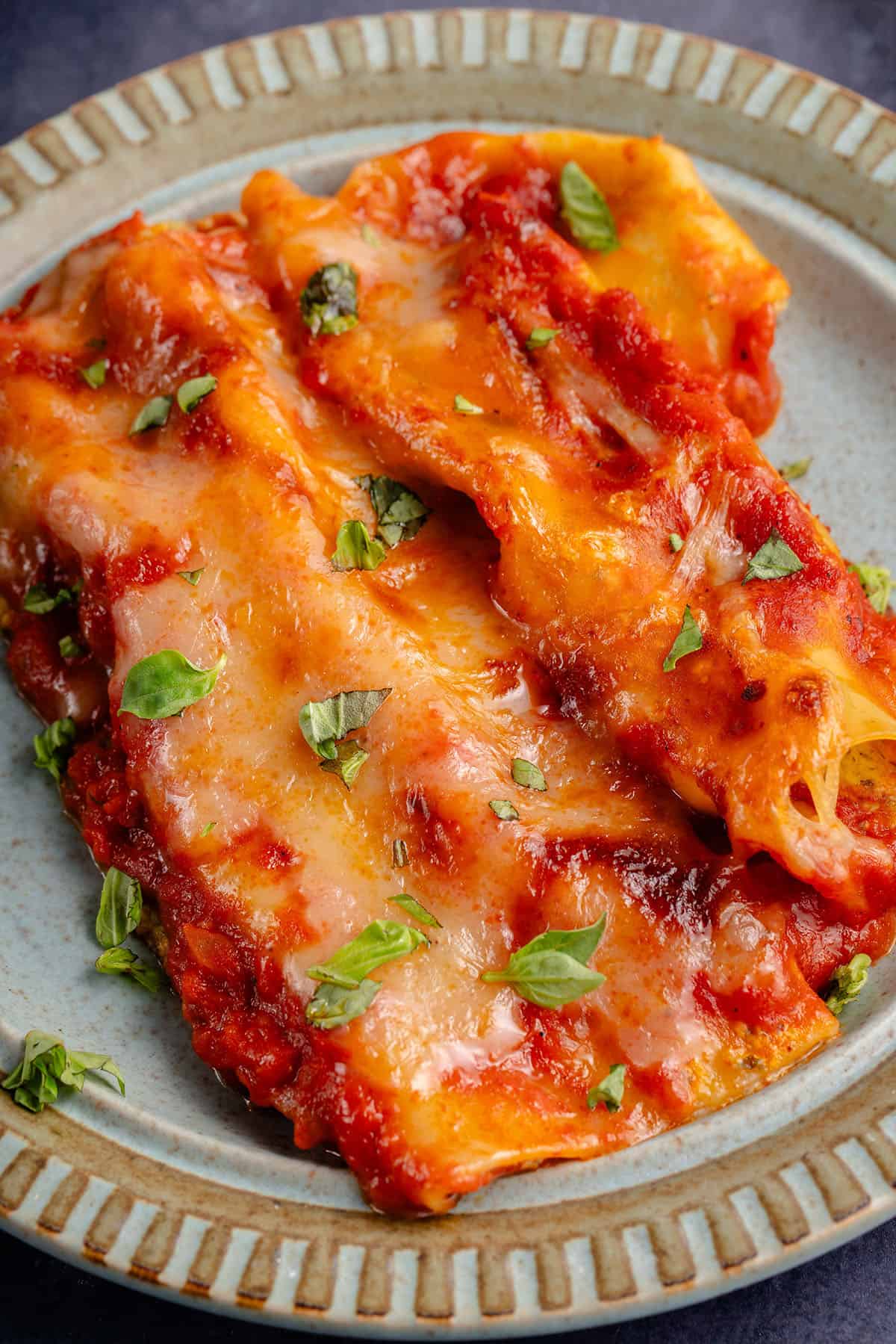 manicotti on a plate with fresh basil