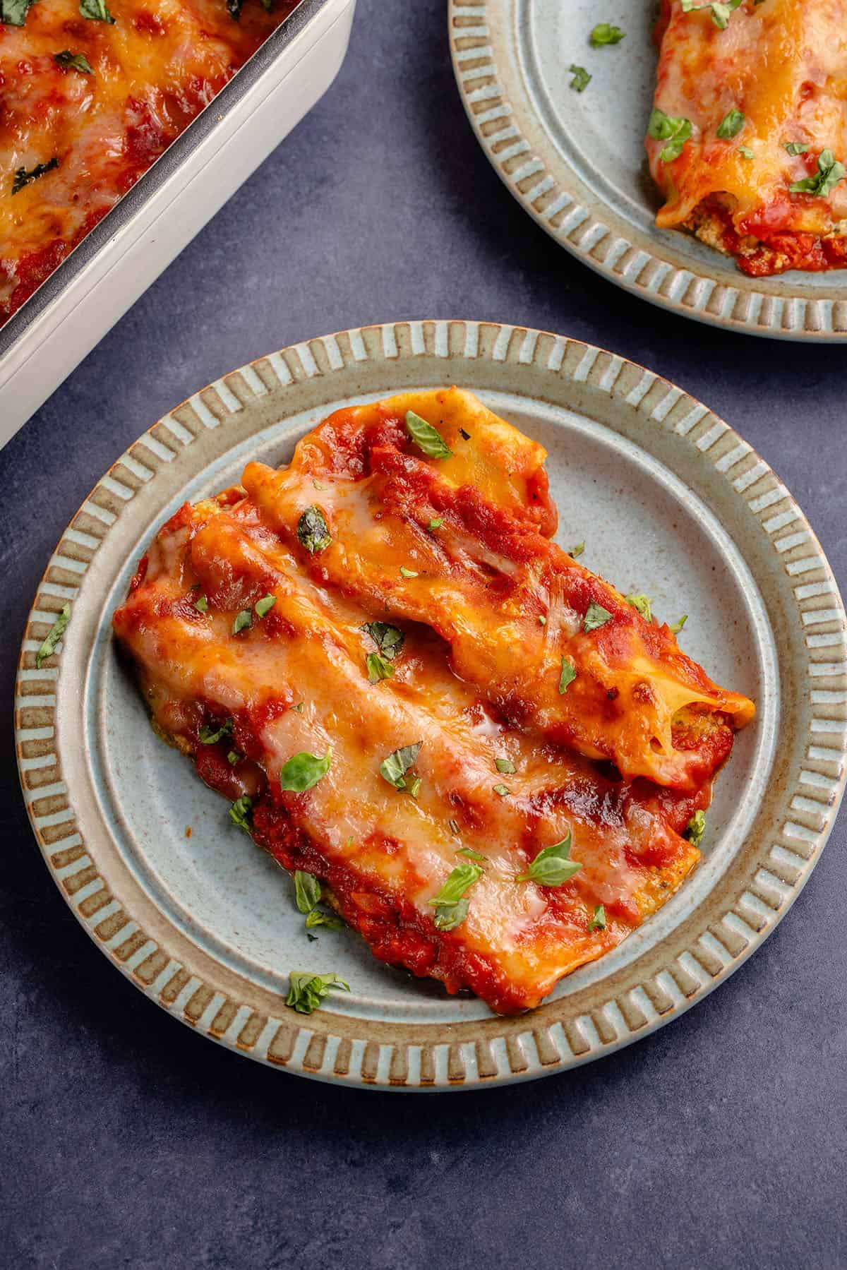 vegan baked manicotti topped with fresh basil on a plate