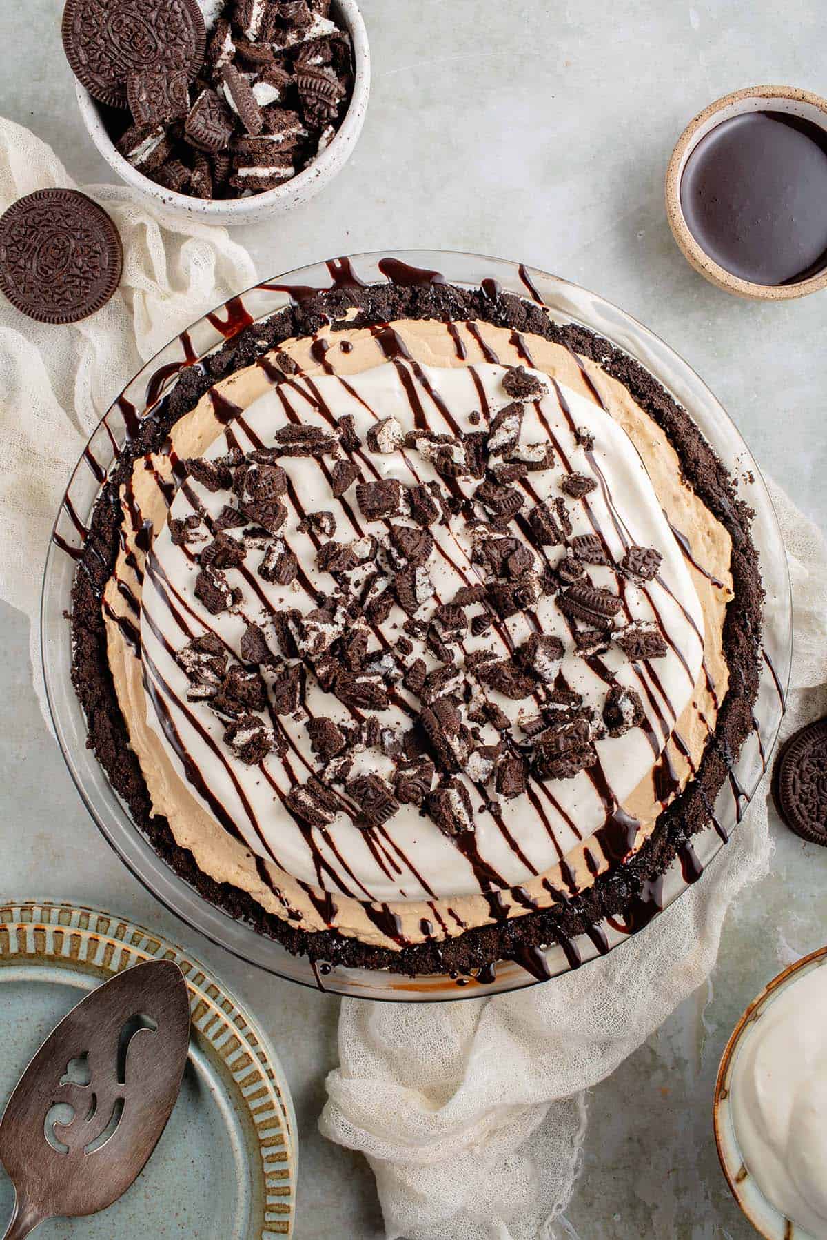 overhead of no bake vegan peanut butter pie drizzled with chocolate syrup and crushed oreo cookies