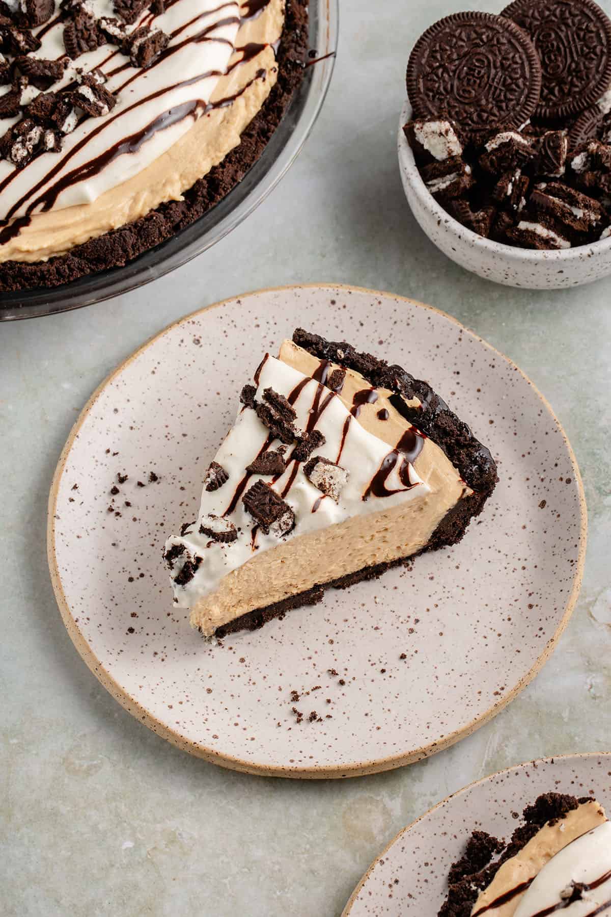 slice of vegan peanut butter pie on a plate with a side of crushed oreos