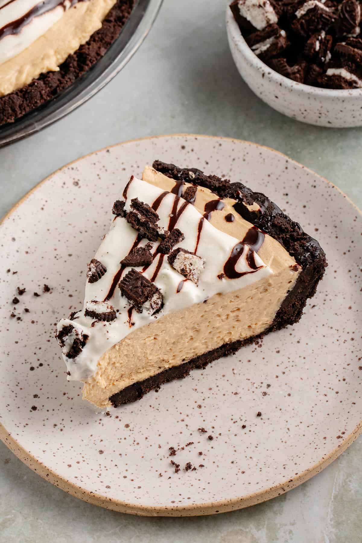 slice of peanut butter pie on a plate with a side of crushed oreos