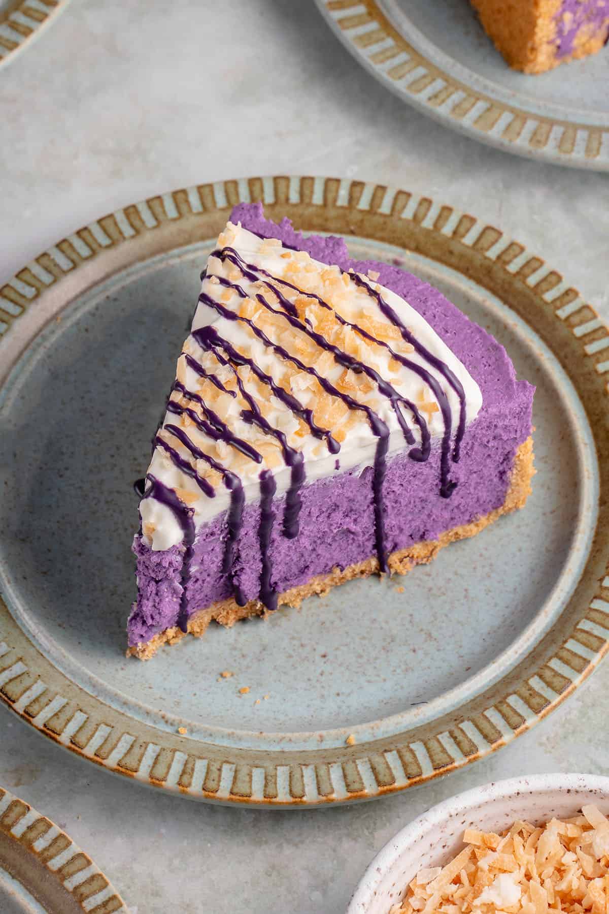 ube cheesecake on a blue plate surrounded by coconut flakes