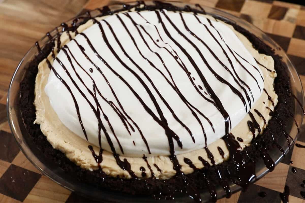 peanut butter pie topped with whipped cream and chocolate syrup