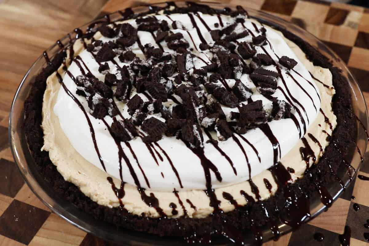 peanut butter pie topped with whipped cream and chocolate syrup and crushed oreo cookies