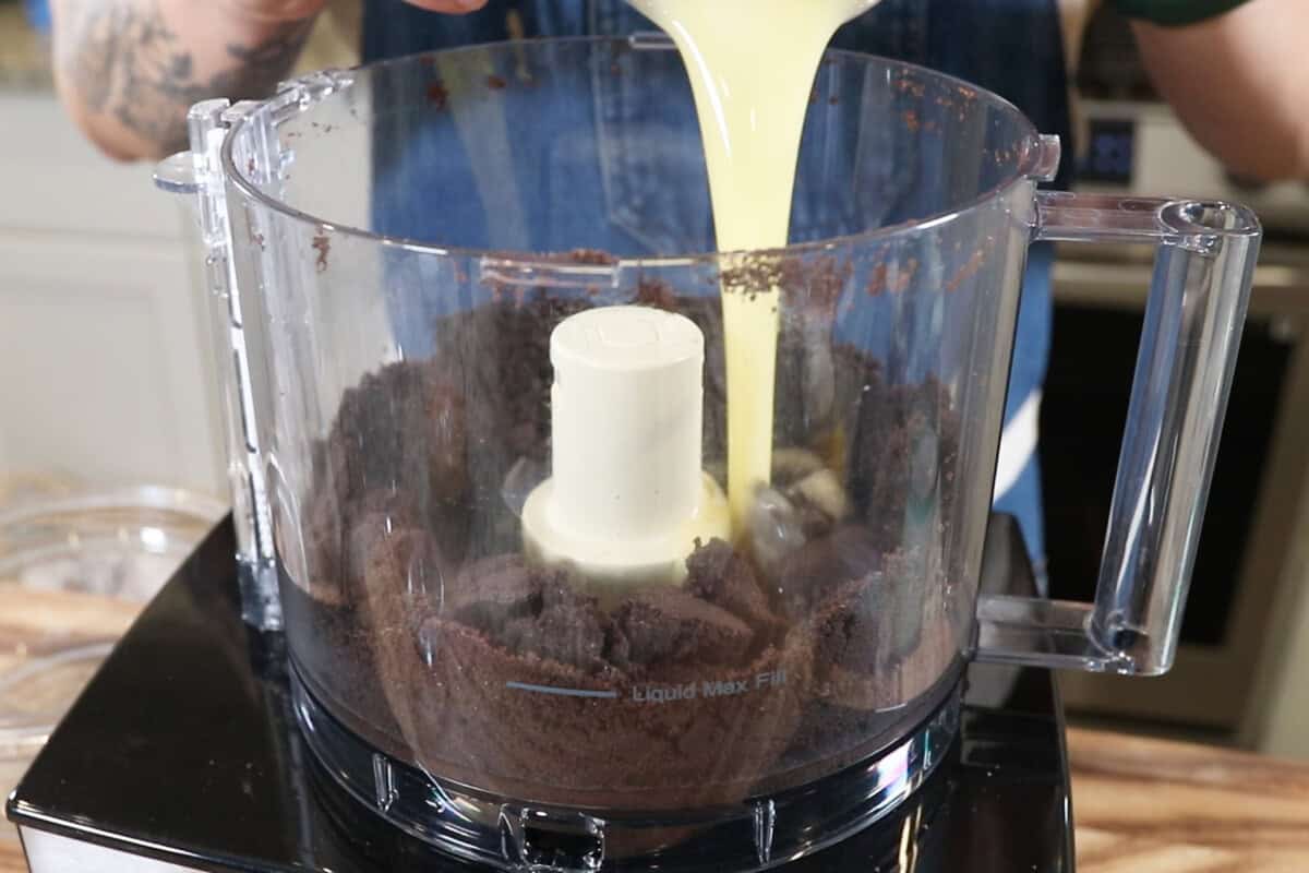 adding dairy-free butter to oreo cookies in a food processor