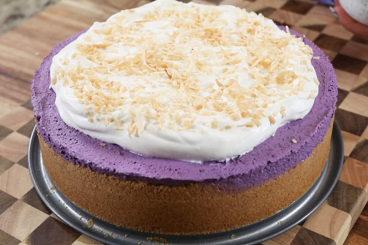 finished ube cheesecake topped with whipped cream and toasted coconut