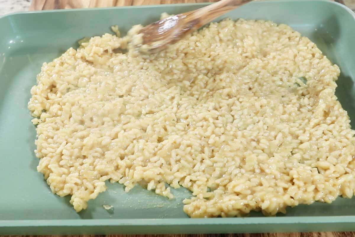 spreading risotto out in an even layer on baking sheet