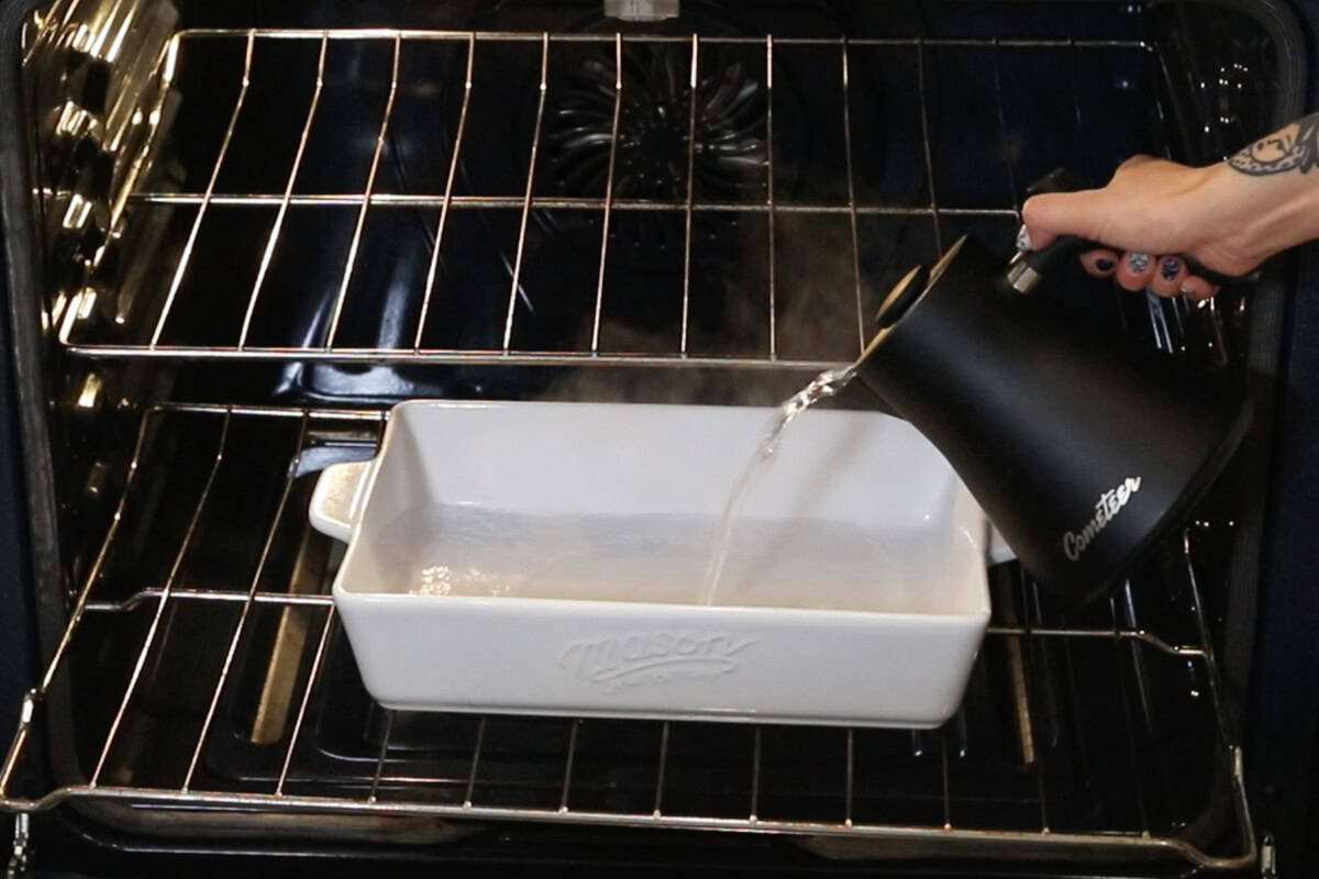 pouring water into a baking dish in oven for cheesecake