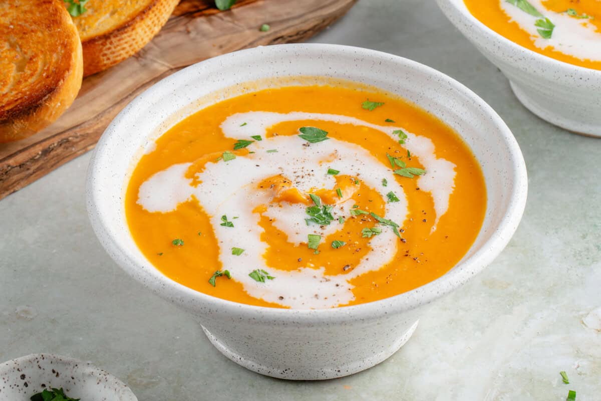 bowl of roasted sweet potato soup topped with coconut milk and parsley